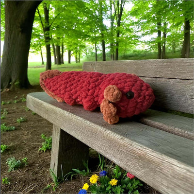 Adorable plush axolotl toy resting on a wooden bench in a lush green park, perfect for custom color orders.